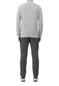 Grau meliertes Strickpullover mit gerippten Bündchen, kombiniert mit dunkelgrauen Cargo-Hosen mit Seitentaschen und schmal zulaufendem Bein, getragen mit weißen Sneakers.