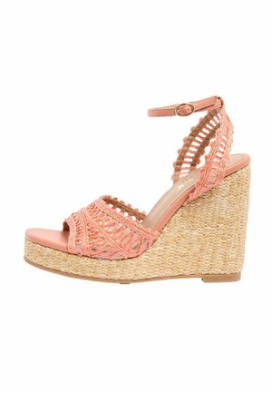 Sandale à talon compensé en paille tissée, avec brides en crochet rose, boucle à la cheville. Design à bout ouvert.