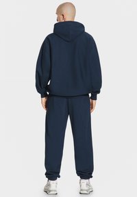 Granatowy panda z dużym kapturem, luźny krój i ściągacze na mankietach, zestawiony z pasującymi spodniami dresowymi z elastycznymi mankietami na kostkach.