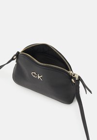 Schwarze Lederhandtasche mit einem goldenen Reißverschluss und einem Logo-Akzent. Innenfutter ist geräumig und mit einem schlanken, verstellbaren Riemen ausgestattet.