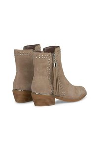 Stivali ankle in suede beige con accenti di borchie argentate, una cerniera laterale e un pon-pon decorativo. Tacco impilato marrone con una finitura liscia.