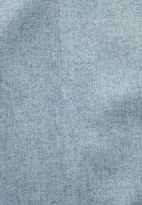 Světle modrá texturovaná tkanina s jemným tkaným vzorem, vykazující měkký a mírně opotřebovaný vzhled.