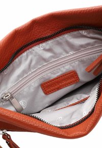 Intérieur d'un sac à main en cuir orange avec une doublure grise, comprenant une poche zippée et une étiquette rectangulaire. Matériau texturé et quincaillerie de zipper lisse.