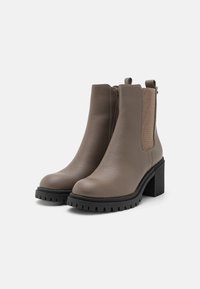 Bottines en cuir marron avec une finition texturée, panneaux latéraux élastiques, semelle en caoutchouc noir épaisse et talon chunky. Design à bout fermé.