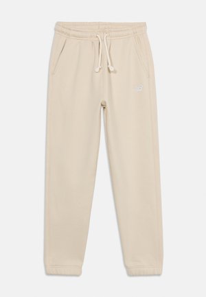 Svetlo béžové jogger nohavice s elastickým pásom, sťahovacou šnúrkou, bočnými vreckami a malým bielym logom na pravej stehne.