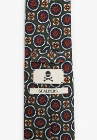 Corbata de tejido con patrones en azul marino, rojo y blanco, con motivos circulares y una etiqueta que dice "SCALPERS" que presenta un icono de calavera.