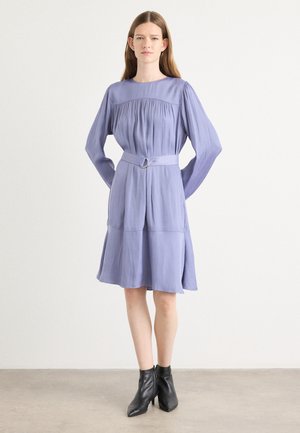 Light lavender dress with long sleeves, gathered bodice, and a waist belt featuring a circular buckle. Knee-length with a flared skirt.