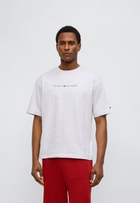 Γκρι βαμβακερό T-shirt με κοντά μανίκια, με το λογότυπο "TOMMY HILFIGER" σε μαύρο και κόκκινο στο στήθος. Χαλαρή εφαρμογή με πλαϊνές σχισμές.