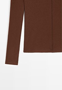 Brown long-sleeve top in a ribbed texture, featuring a straight hem and a simple design without visible fastenings or embellishments.