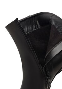 Bottine en cuir noir avec une fermeture éclair sur le côté, dotée d'une doublure intérieure douce noire et d'une finition extérieure lisse.