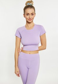 Top cropped din lavandă, cu mâneci scurte, asortat cu colanți cu talie înaltă. Textură netedă, design ajustat, detalii subtile ale cusăturilor.