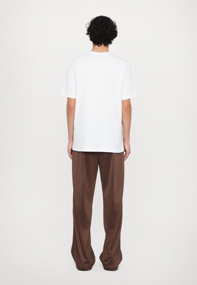 White cotton t-shirt and brown relaxed-fit trousers. T-shirt has a crew neckline, and trousers feature a smooth, flowing texture and wide leg.