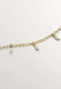 Collar de cadena de oro con eslabones redondeados y tres cuentas colgantes con un acabado mate. Textura suave con un aspecto pulido.