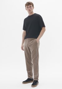 Black cotton t-shirt paired with brown corduroy pants and black sneakers. Simple design with relaxed fit and elastic waistband.