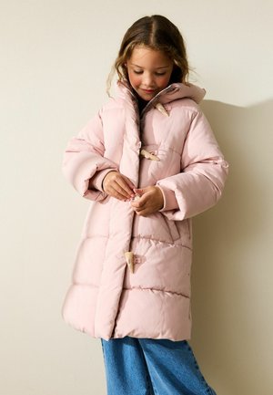 Geacă roz căptușită cu glugă, prevăzută cu nasturi tip toggle și design matlasat. Modelul poartă pantaloni din denim albastru, evidențiind un look casual.