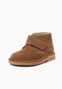 Botte en cuir suédé marron à hauteur de cheville avec une sangle Velcro, bout rond et semelle en caoutchouc. Dispose de détails cousus le long des bords et d'un doublure lisse.