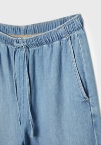 Ljusblå denim joggers med elastisk midja, dragsko och sidofickor. Mjuk textur och avslappnad passform.