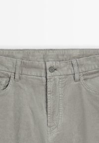 Pantaloni in corduroy grigi con vita piatta, chiusura con bottone in metallo e tasche laterali con texture a righe verticali.