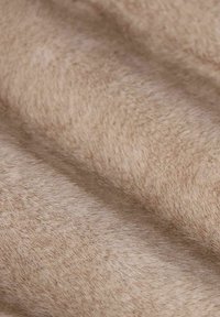 Tissu beige doux avec une texture lisse, présentant de légères variations de couleur et un brillant subtil, idéal pour l'ameublement ou l'usage vestimentaire.