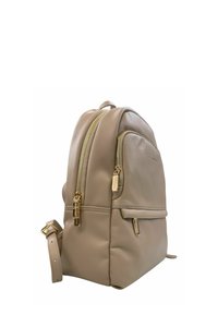 Zaino in pelle beige con forma arrotondata, doppie cerniere e dettagli in metallo dorato. Presenta una tasca anteriore e una tracolla regolabile.