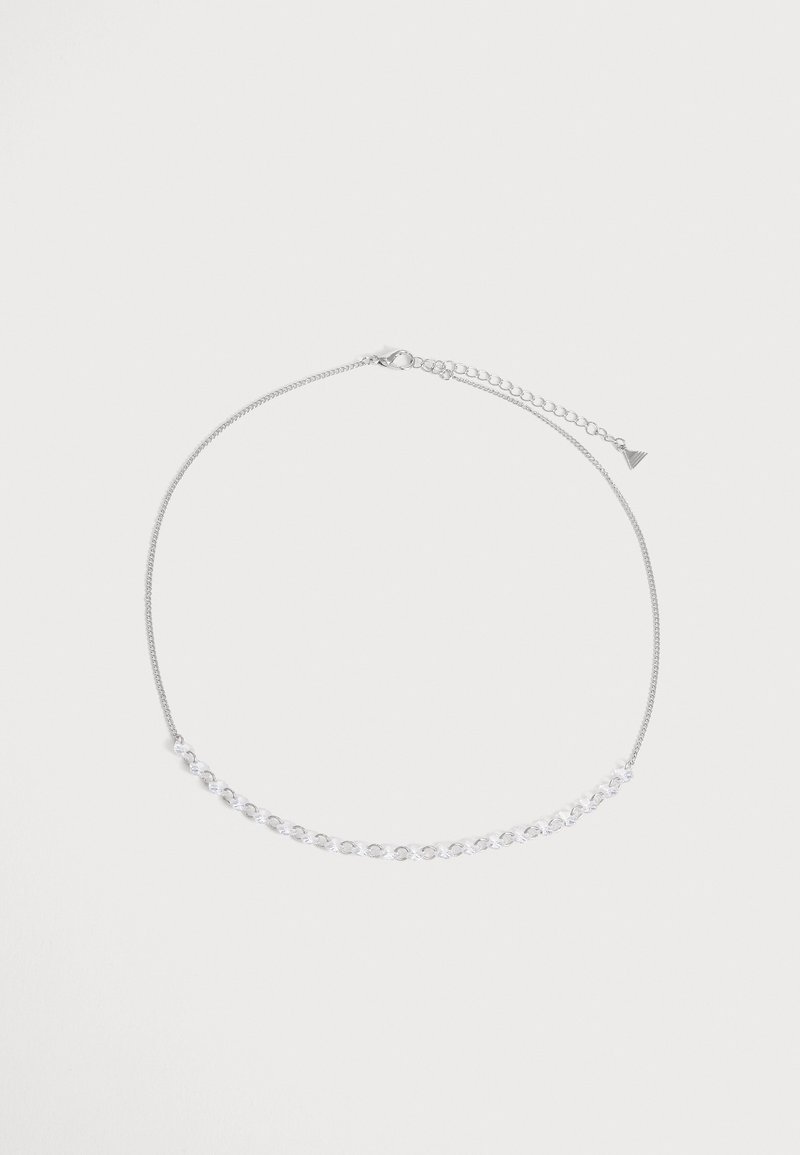 Collier chaîne en argent avec une petite partie reliée à l'avant et un fermoir réglable sur un fond uni et clair.