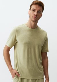 Jasnozielona koszulka z krótkim rękawem z miękkiego, teksturowanego materiału, z okrągłym dekoltem i luźnym fasonem, podkreślająca casualowy charakter.