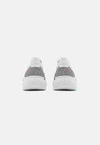 Gray and white athletic shoes feature a textured fabric upper, a reinforced grey heel, and a white rubber sole. Simple, streamlined design.