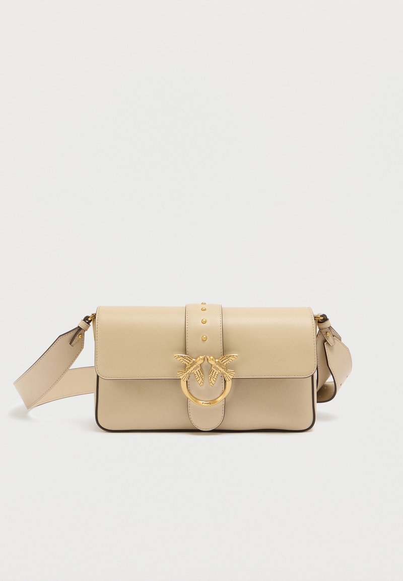 Τζιν τσάντα χειρός από δέρμα σε μπεζ χρώμα με κούμπωμα σε χρυσό τόνο που διαθέτει σχέδια πουλιών, τρεις διακοσμητικές καρφίτσες και αποσπώμενο ιμάντα. Στρογγυλεμένες άκρες και λεία υφή.