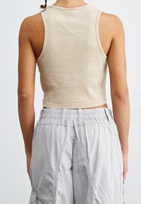 Beige randig kort topp med rund halsringning, matchad med ljusgrå cargoshorts med elastisk midja och sidofickor.