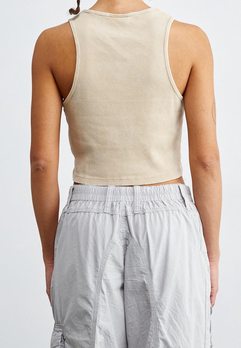 Beige randig kort topp med rund halsringning, matchad med ljusgrå cargoshorts med elastisk midja och sidofickor.