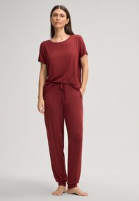 Bordeaux-Loungewear-Set mit einem T-Shirt mit kurzen Ärmeln und einer Hose mit Kordelzug, aus glattem Stoff gefertigt, mit entspanntem Schnitt und dezentem Logo.