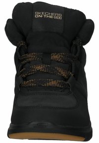 Baskets Skechers ON-THE-GO noires avec un col rembourré, des lacets tissés texturés en marron, un matériau supérieur lisse et une semelle en caoutchouc.