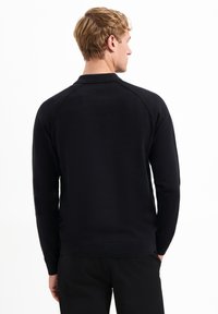 Zwarte lange mouwen pullover trui met een gladde textuur, geribbelde zoom en kraag. Kenmerken raglanmouwen voor gemakkelijke beweging.