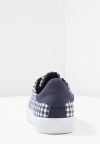 Granatowo-białe trampki wykonane z płótna w kratkę gingham, z białą gumową podeszwą i wyściełanym kołnierzem, z ozdobnym przeszyciem na tyle.