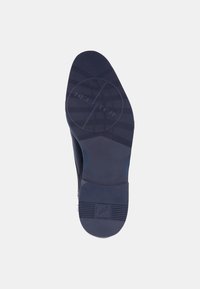 Semelle de chaussure bleu foncé avec une surface texturée, présentant un motif circulaire et un logo en relief. Talon léger et matériau en caoutchouc flexible.