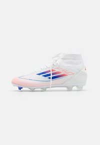 Vita fotbollssko med blå och röda gradientränder, strumpaktig krage vid ankeln och dobbar på sulan för bra grepp på gräsplaner.