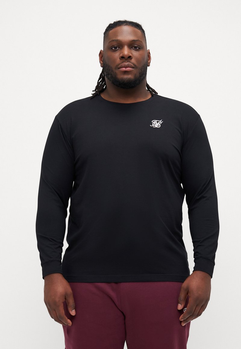 Long-sleeve black t-shirt made of lightweight fabric, featuring a small white logo on the chest. Smooth texture with a round neckline.