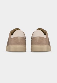 Ζεύγος μπεζ σουέντ αθλητικών παπουτσιών με ελαφρώς ταμπά σόλες, εμφανιζόμενα από την πίσω πλευρά σε ένα απλό λευκό φόντο.