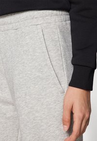 Graue Sweatpants mit texturierter Oberfläche, ausgestattet mit Fronttaschen und einem schwarzen Rippenbund. Der Bund ist elastisch für zusätzlichen Komfort.
