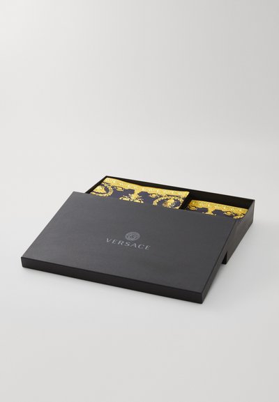 Melna taisnstūra kaste ar zelta akcentētu rakstu ieliktņiem. Virsmas augšdaļā ir Versace logo sudrabā.