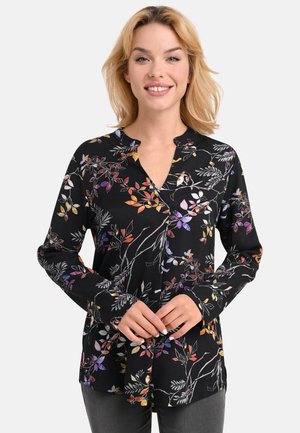 Schwarze Bluse mit langen Ärmeln und einem floralen Muster in lebhaften Farben, mit V-Ausschnitt und geradem Schnitt. Der Stoff wirkt glatt und leicht.