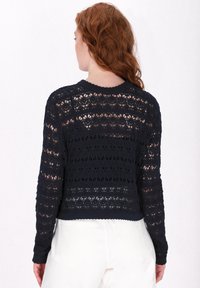 Granatowy sweter na szydełku z długimi rękawami i ribbowym dekoltem. Posiada wzór ażurowy z teksturowanym wykończeniem oraz skrócony fason.