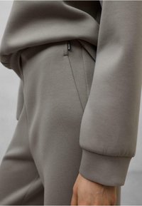 Felpa grigia chiara, con texture, dotata di polsini a costine e dettagli con tasca. Tessuto morbido con vestibilità elasticizzata. Etichetta distintiva sulla cucitura.