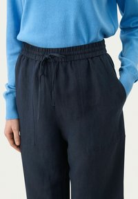 Pantaloni in misto lino blu navy con vita elastica e coulisse. Presentano tasche laterali e un design a vestibilità rilassata.