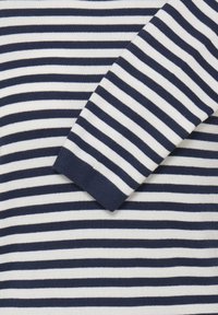 Pull tricoté rayé bleu marine et blanc avec des poignets côtelés. La texture est lisse, avec des rayures horizontales uniformément espacées sur toute la surface.