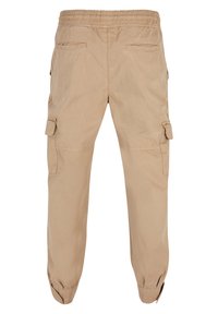 Beige Cargo-Hosen mit elastischem Bund, seitlichen Cargo-Taschen und elastischen Bündchen. Hergestellt aus leichtem Stoff, für Komfort und Funktionalität konzipiert.