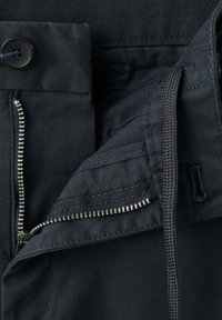 Czarna talia spodni z częściowo rozpiętym srebrnym zamkiem błyskawicznym, czarnym guzikiem i widocznym czarnym sznurkiem do wiązania.