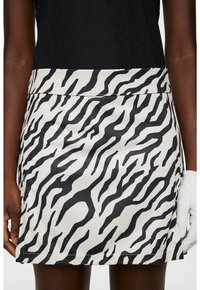 Randig kjol i zebra-mönster med svart och vitt färgschema, tillverkad av mjukt tyg med en åtsittande midja och skräddarsydd fåll.