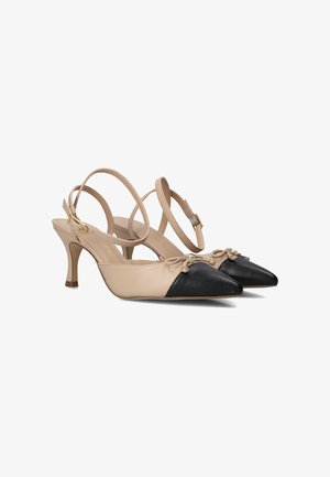 Chaussures slingback en cuir beige avec un bout pointu noir, ornées d'un nœud décoratif et d'accents en métal doré ; talon de 3 pouces.