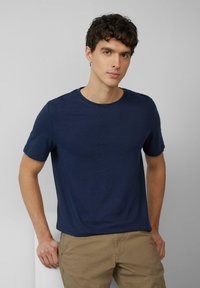 Navyblaue Kurzarm-T-Shirt aus weichem Stoff, mit Rundhalsausschnitt und lockerer Passform, kombiniert mit beige Shorts.